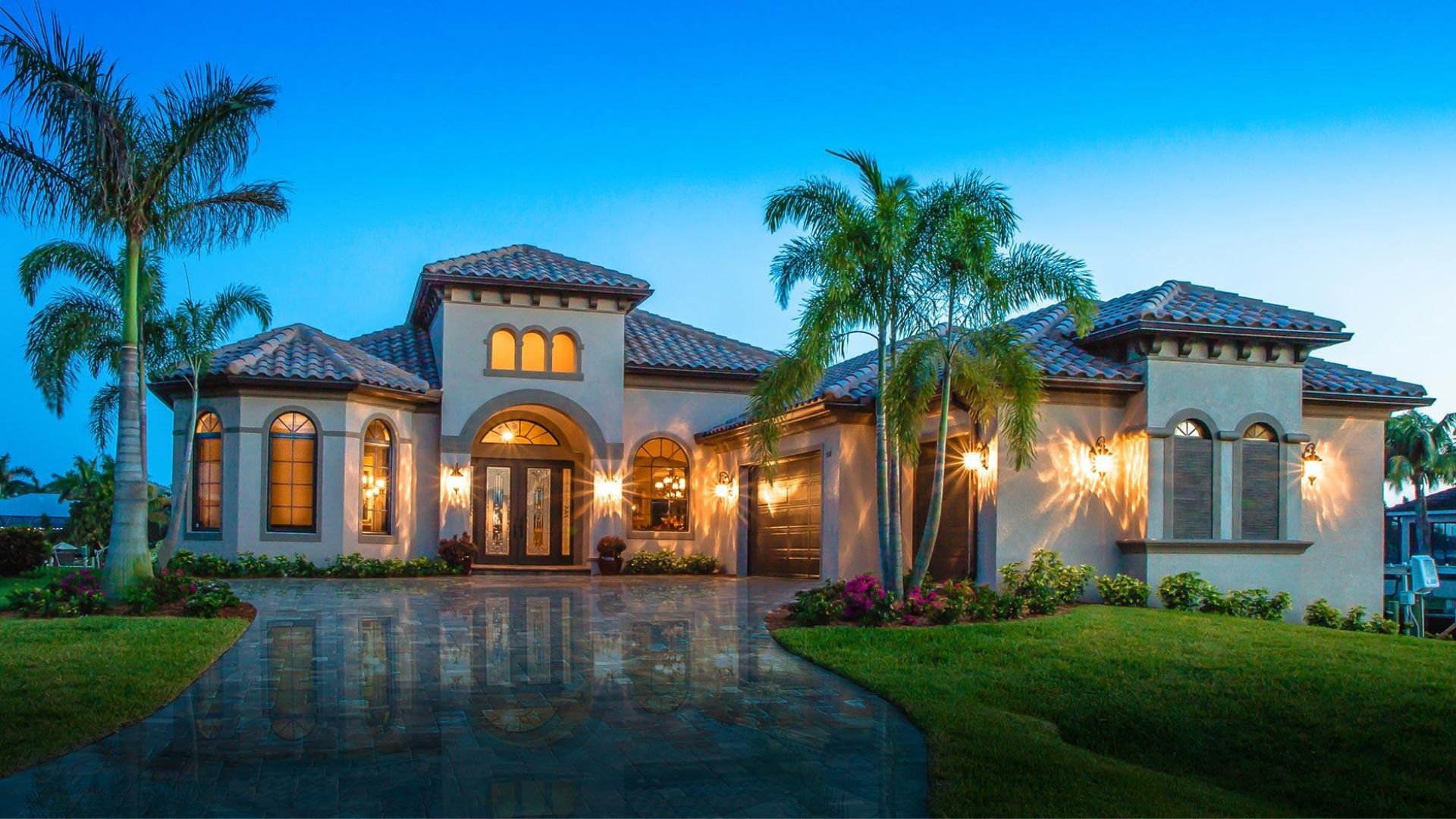 Mediterranean villa with palms and grand entryway at twilight